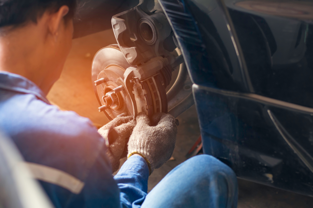 An auto repair technician working on the brakes of a car.