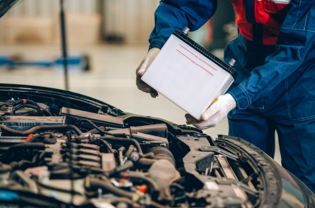 Auto repair technician installing a car battery.