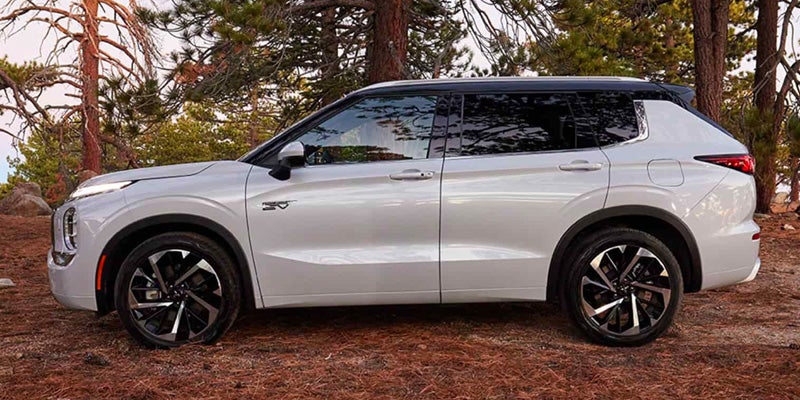 A white 2024 Mitsubishi Outlander PHEV viewed from a side angle.
