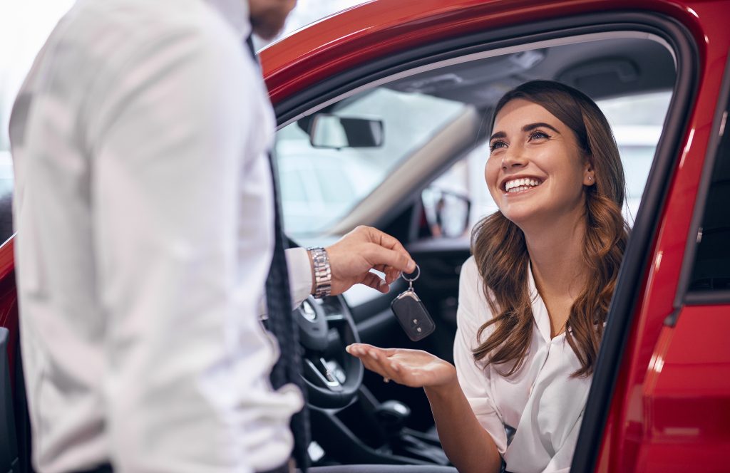 Crop Male Manager Giving Car Keys To Delighted Woman In New Car
